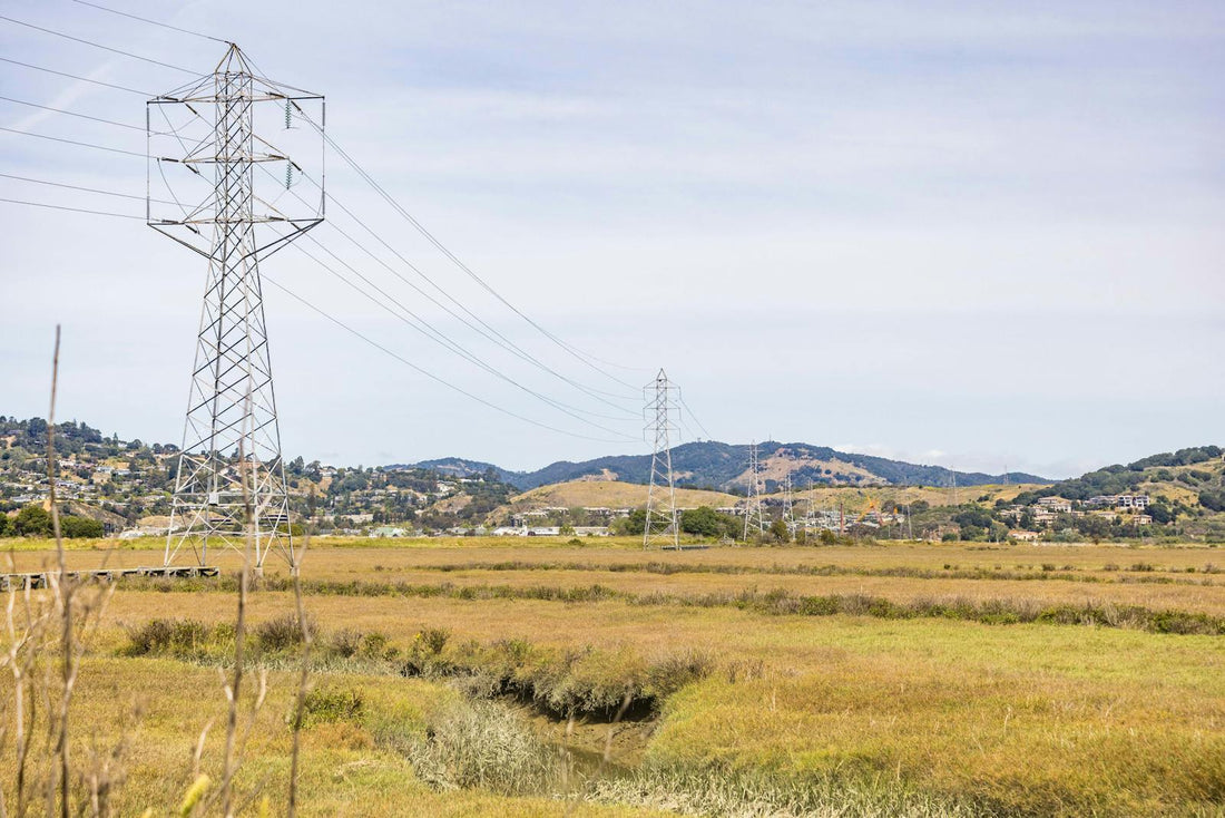 Hoogspanningsmasten en elektriciteitsnet door open landschap, symbool voor netcongestie en thuisbatterij-aansturing in 2026