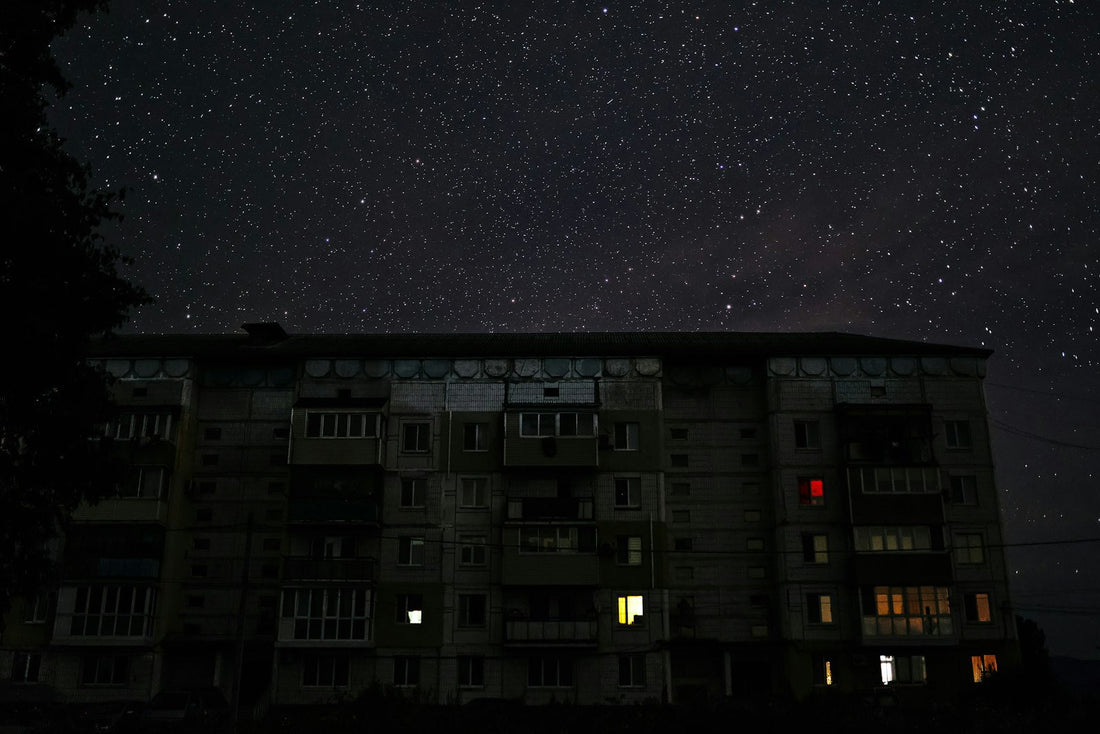 Donker woonhuis 's nachts met enkele verlichte ramen tijdens stroomuitval, voorbeeld noodstroom thuisbatterij Deye