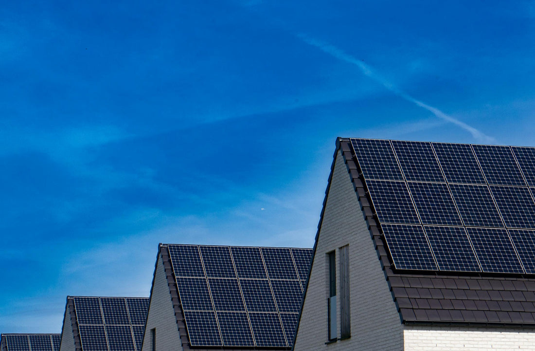 Rij witte bakstenen huizen met zonnepanelen op puntdaken voor thuisbatterij dimensionering bij warmtepomp