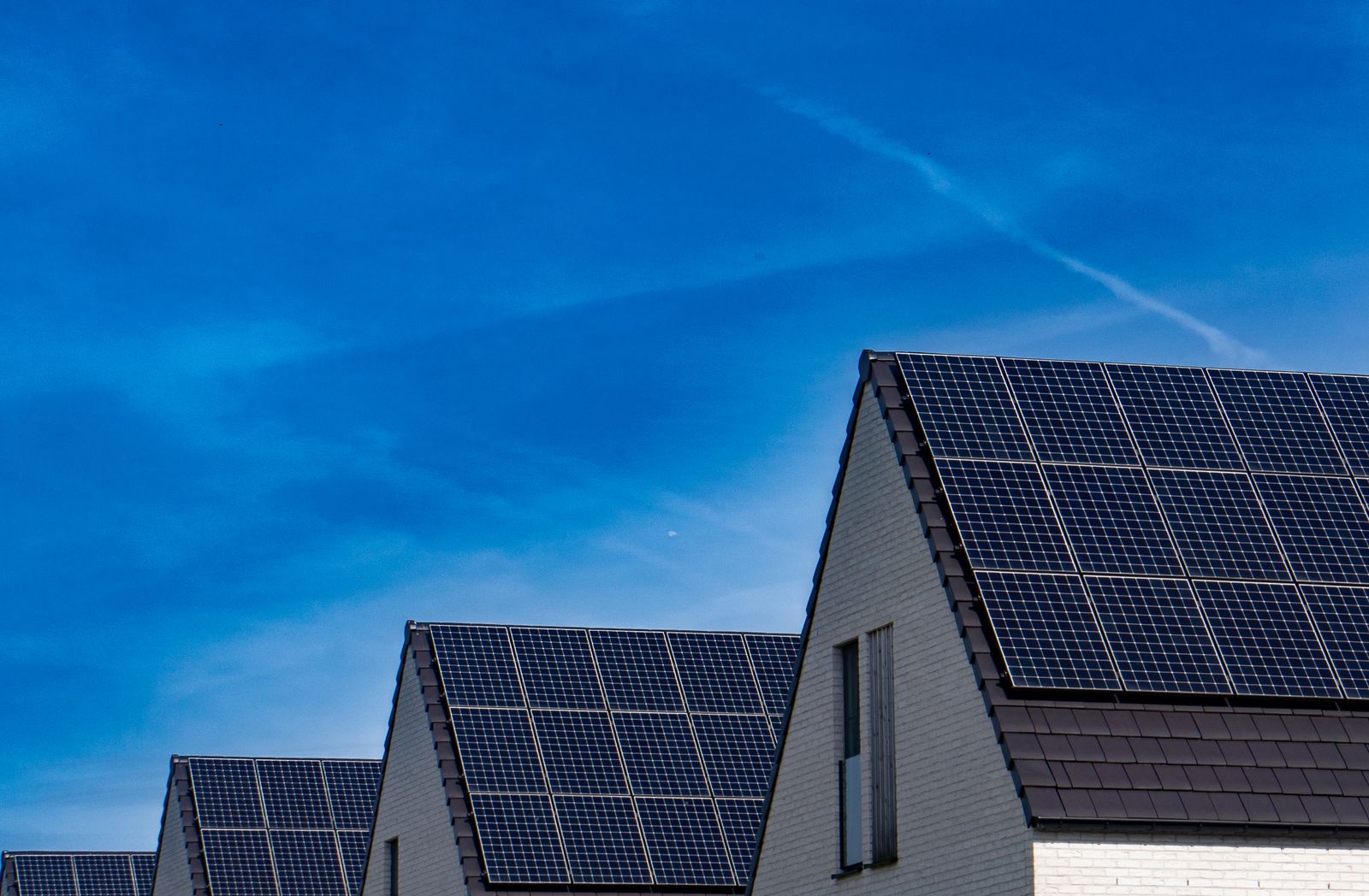 Rij Nederlandse rijwoningen met zonnepanelen op puntdaken onder een blauwe lucht, context voor de vergelijking tussen Deye en SolarEdge thuisbatterij in 2026.