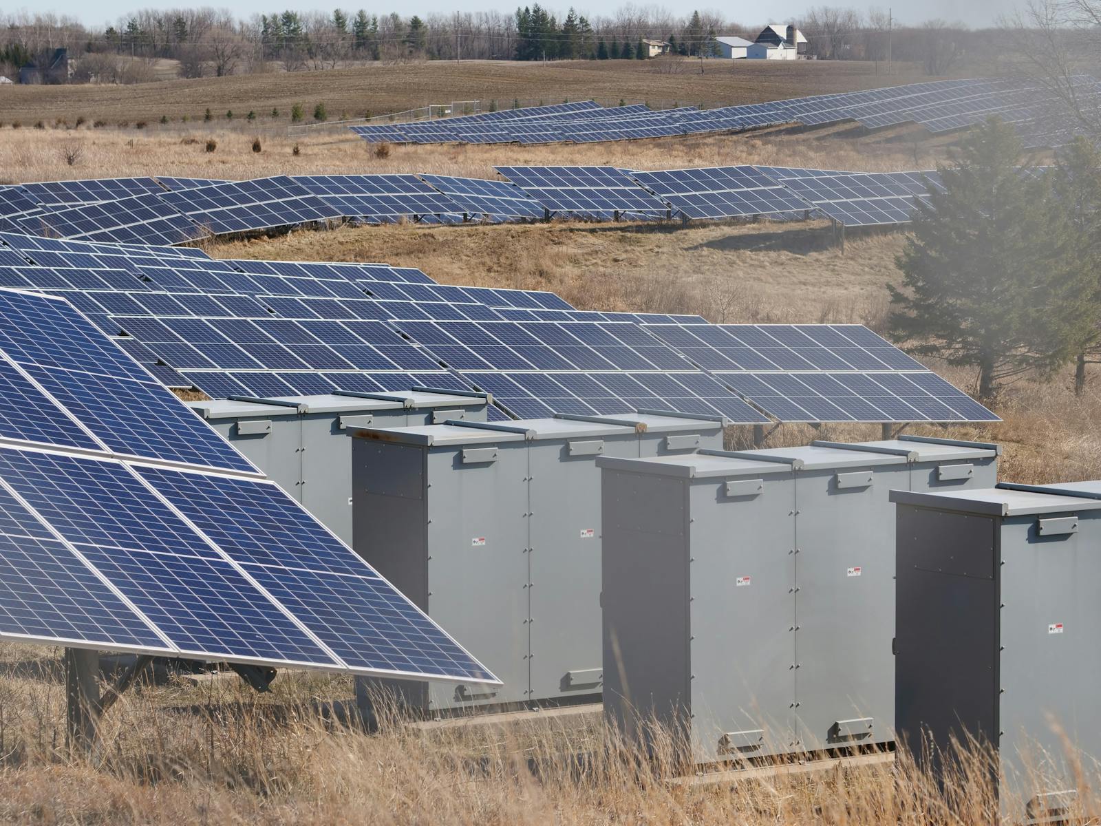Zonnepanelen-veld met grijze batterij-opslagkasten en omvormers voor commerciele MKB-energieopslag