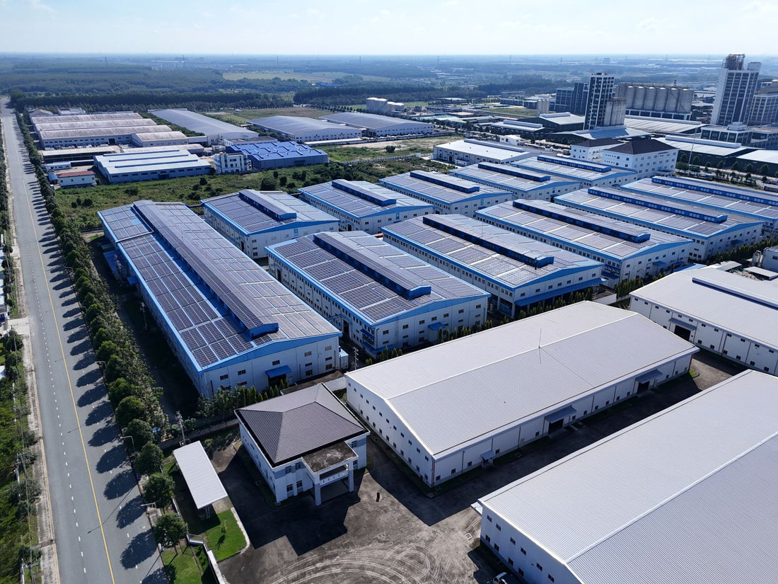 Aerial view industrieel bedrijventerrein met grote PV-installaties op warehouse-daken, context voor zakelijke batterijopslag