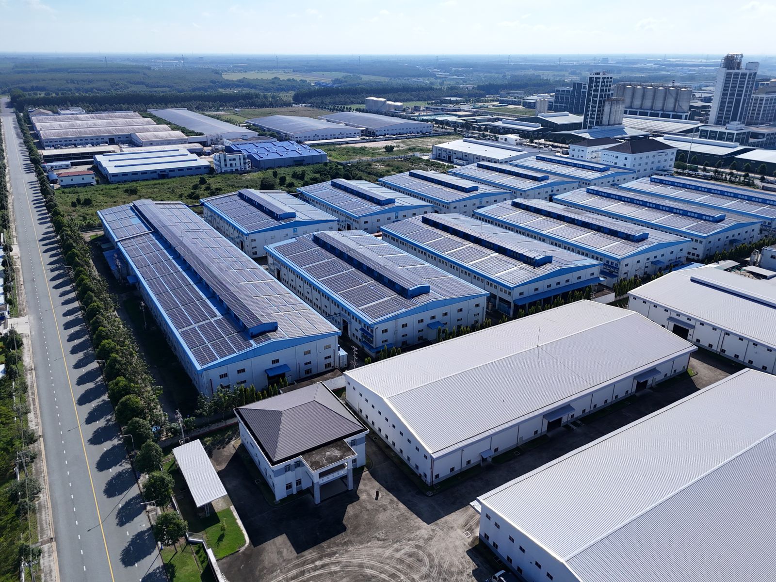 Aerial view industrieel bedrijventerrein met grote PV-installaties op warehouse-daken, context voor zakelijke batterijopslag
