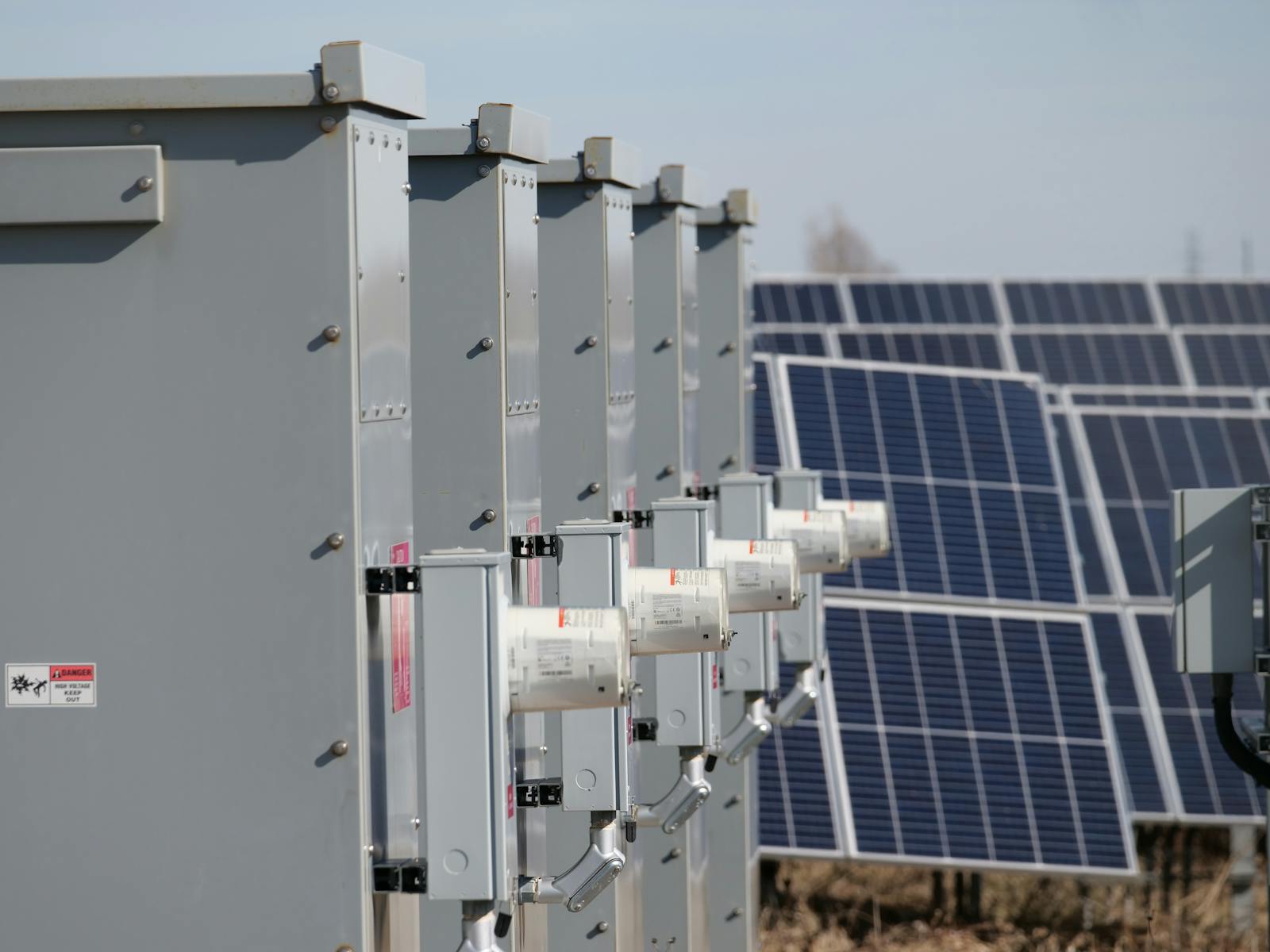 Industriele batterijopslag-cabinets met hoogspanningsstickers naast zonnepanelen, illustratief voor PGS 37