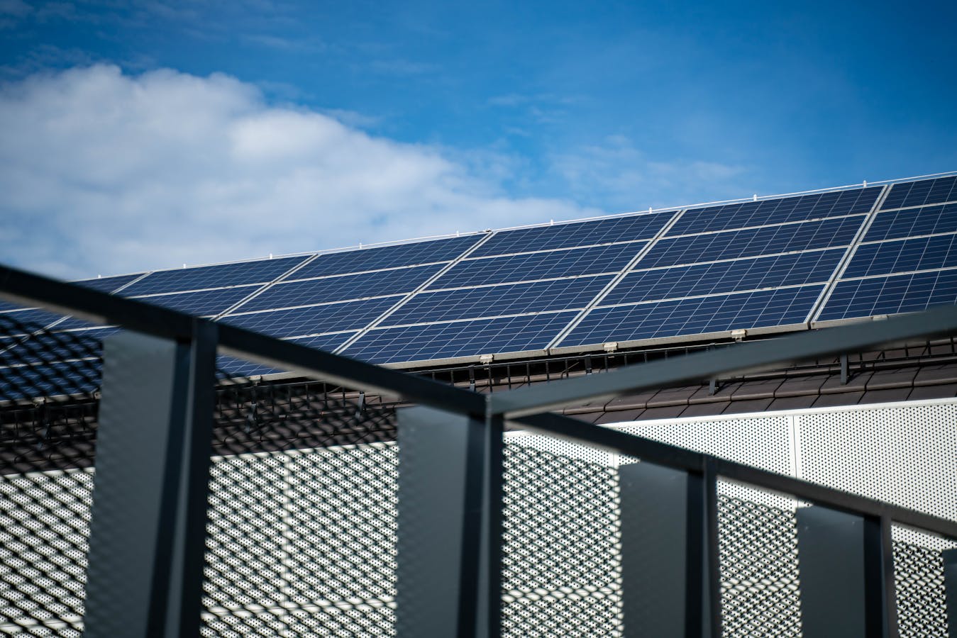 Close-up van moderne blauwe zonnepanelen op een woondak tegen een heldere blauwe lucht, illustratie bij de keuze van het juiste omvormer-vermogen in 2026