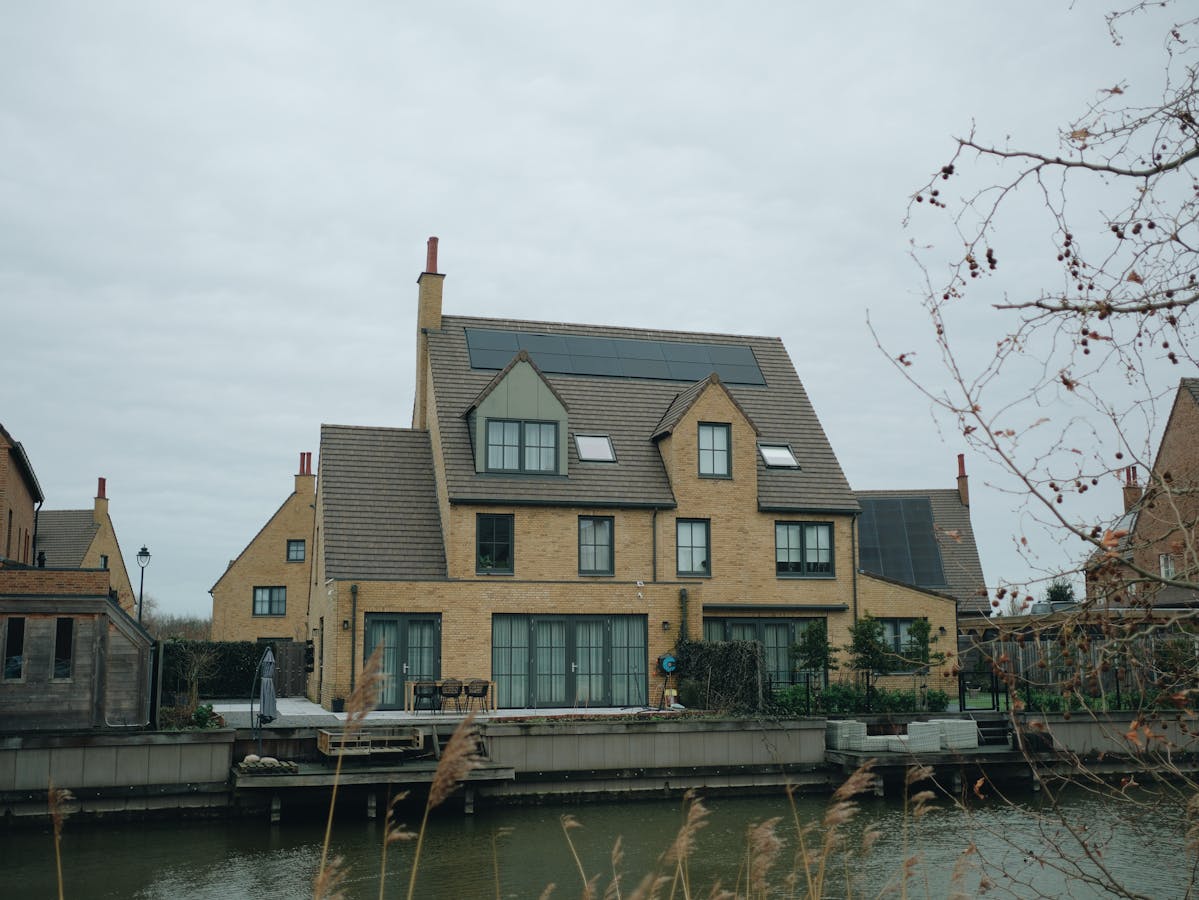 Moderne Nederlandse woning aan een gracht met zonnepanelen op het dak, representatief voor huishoudens die thuisbatterij-capaciteit berekenen