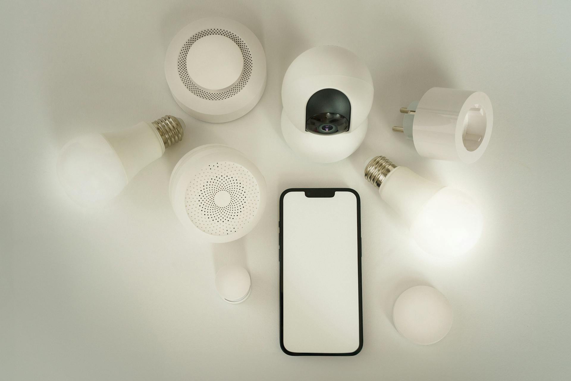Smart home flat-lay met smartphone, slimme stekkers en sensoren op witte achtergrond, illustratie bij Deye Cloud en Copilot setup gids 2026