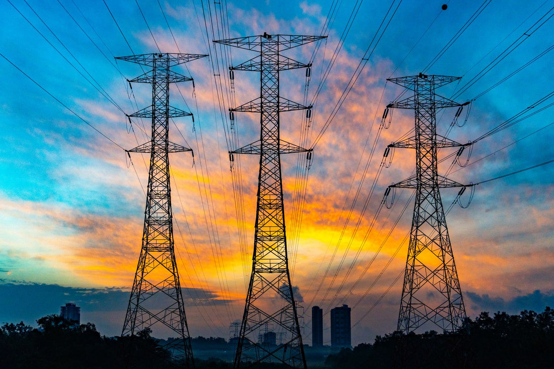 Hoogspanningsmasten bij zonsondergang als beeld voor dynamische energieprijzen en slim laden met een thuisbatterij