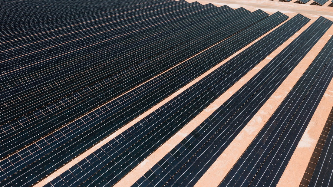 Aerial overzicht van een veld met zonnepanelen-rijen onder helder zonlicht, illustratie bij de Deye firmware update procedure 2026 voor hybride omvormers