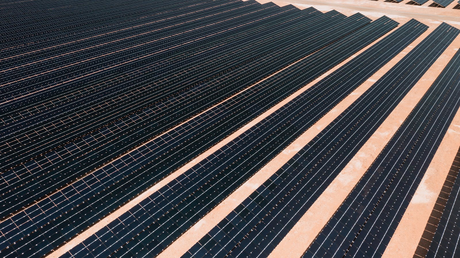 Aerial overzicht van een veld met zonnepanelen-rijen onder helder zonlicht, illustratie bij de Deye firmware update procedure 2026 voor hybride omvormers