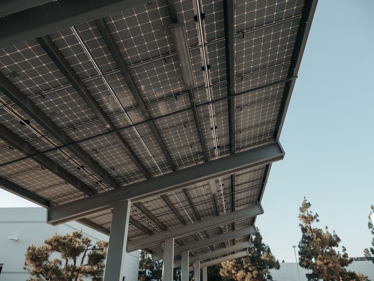 Onderaanzicht van een zonnepaneel-canopy met blauwe lucht erachter, beeld bij de uitleg hoe een Deye hybride omvormer in 2026 werkt